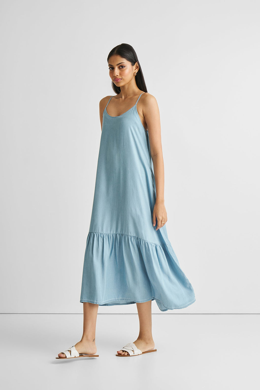 Woman wearing a light blue slip dress on a white background