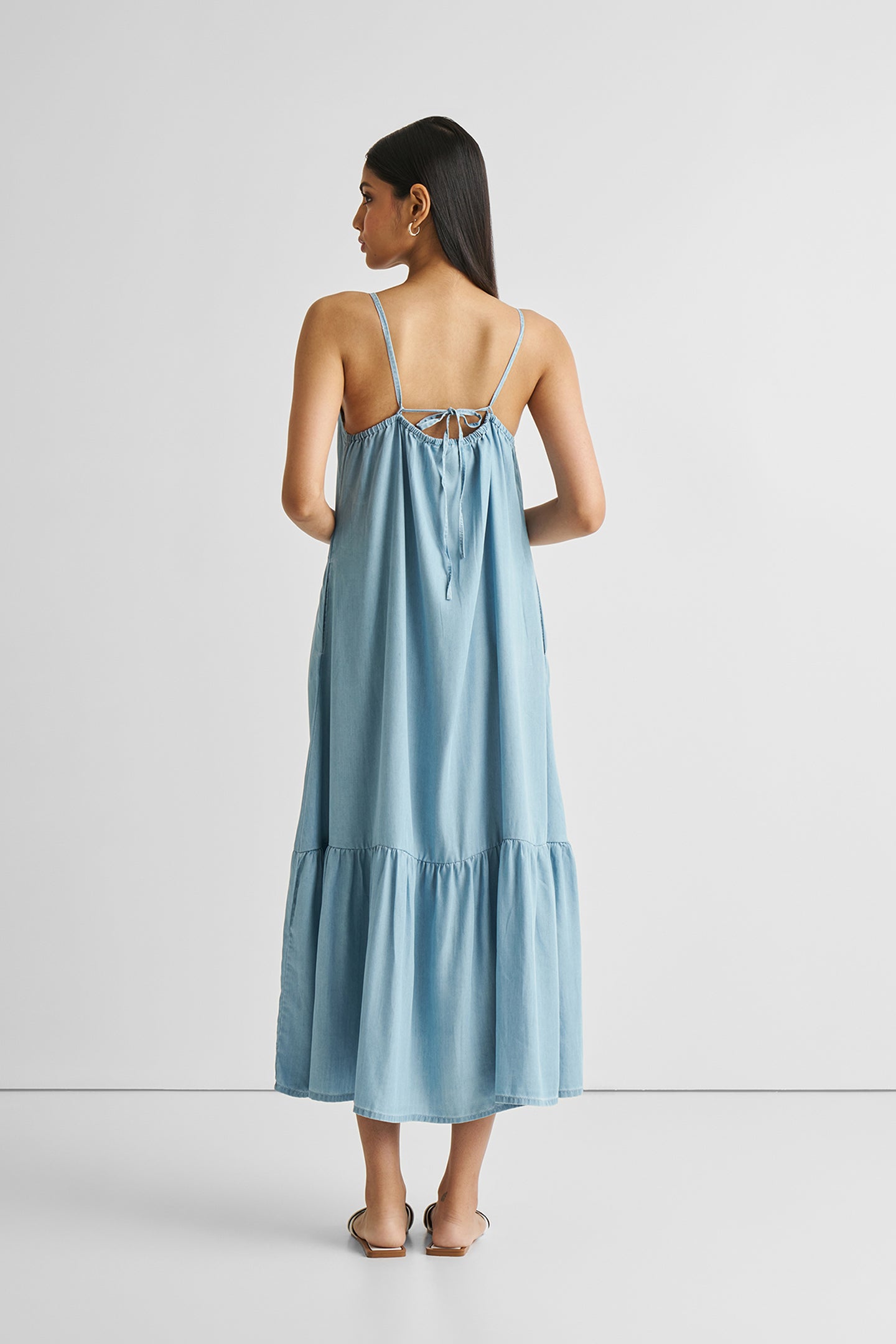 Woman wearing a light blue dress with thin straps on a white background