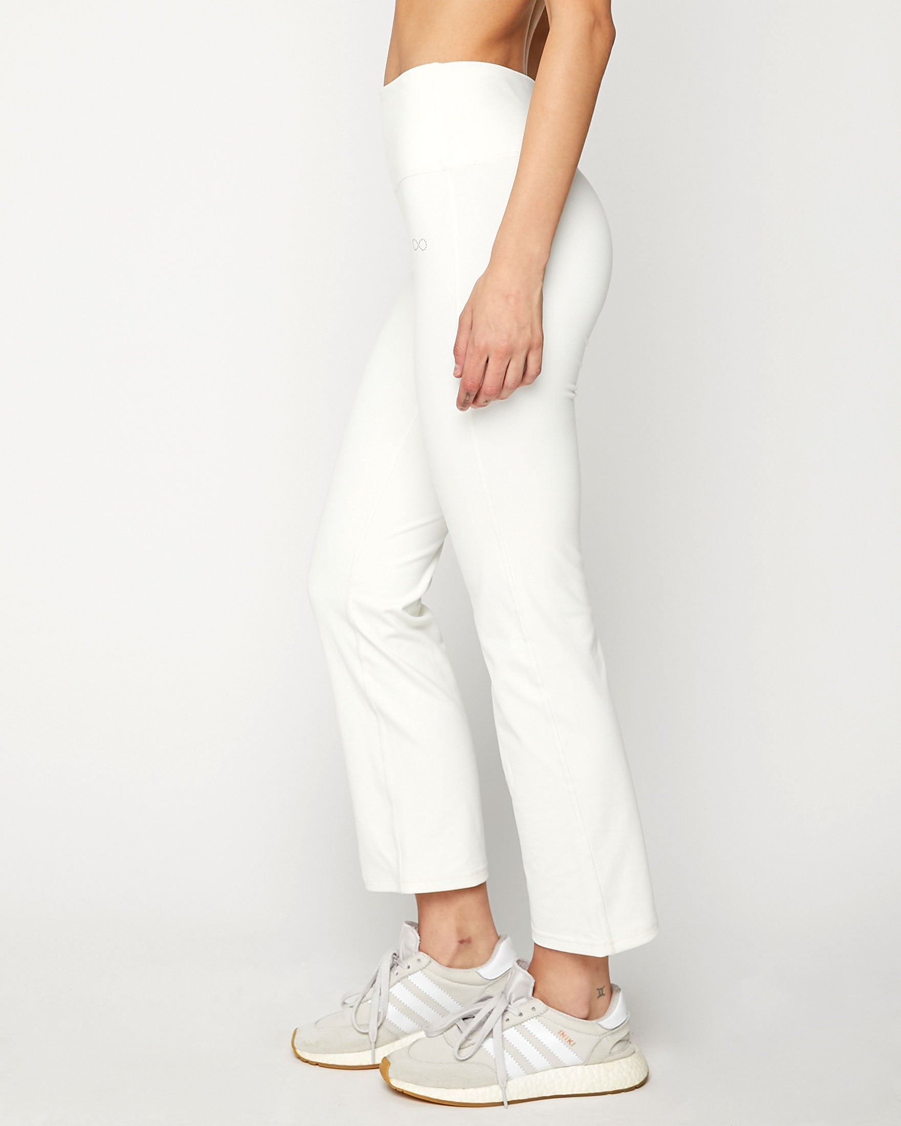 Person wearing white pants and white sneakers on a plain background