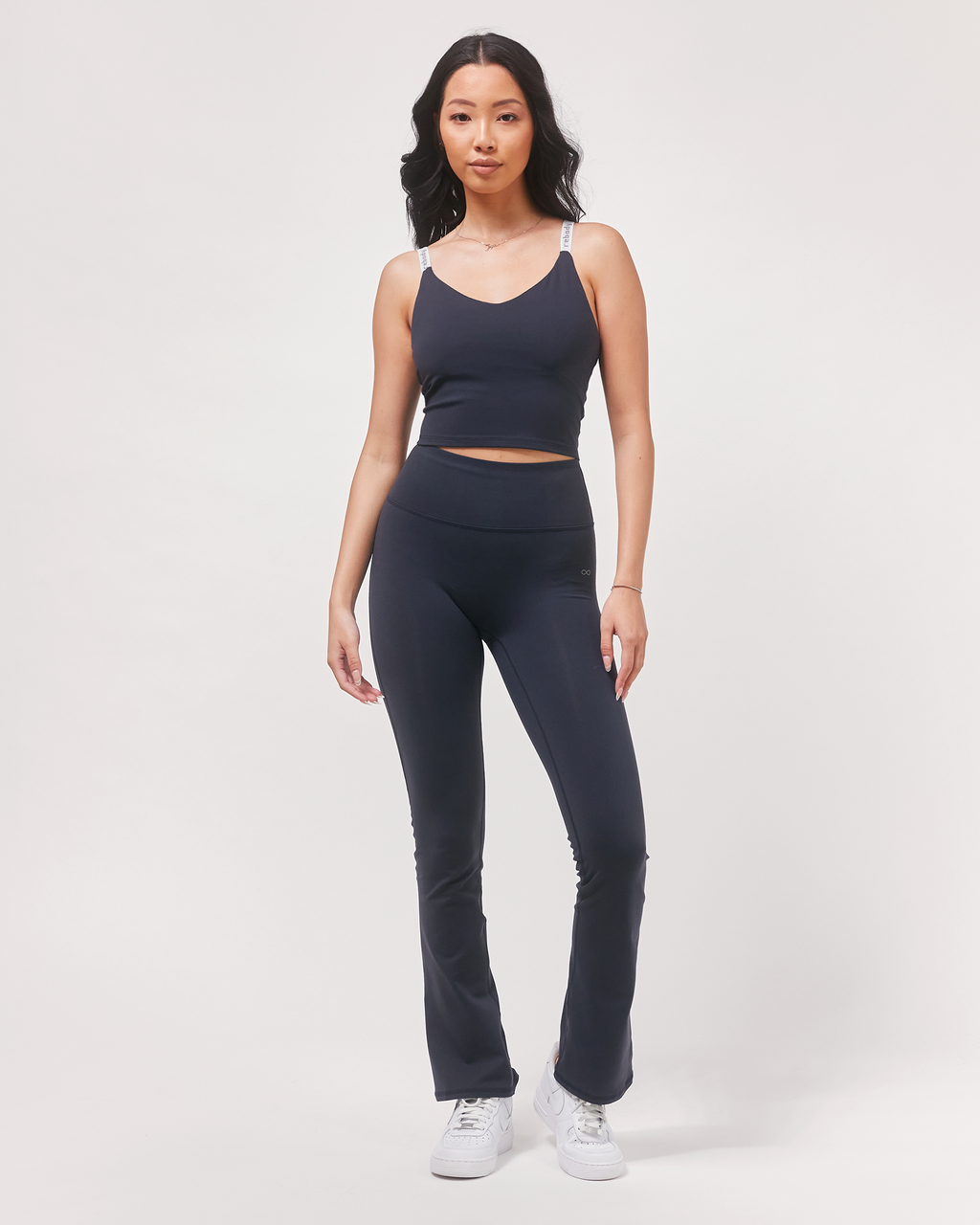 Woman wearing a navy tank top and leggings on a white background