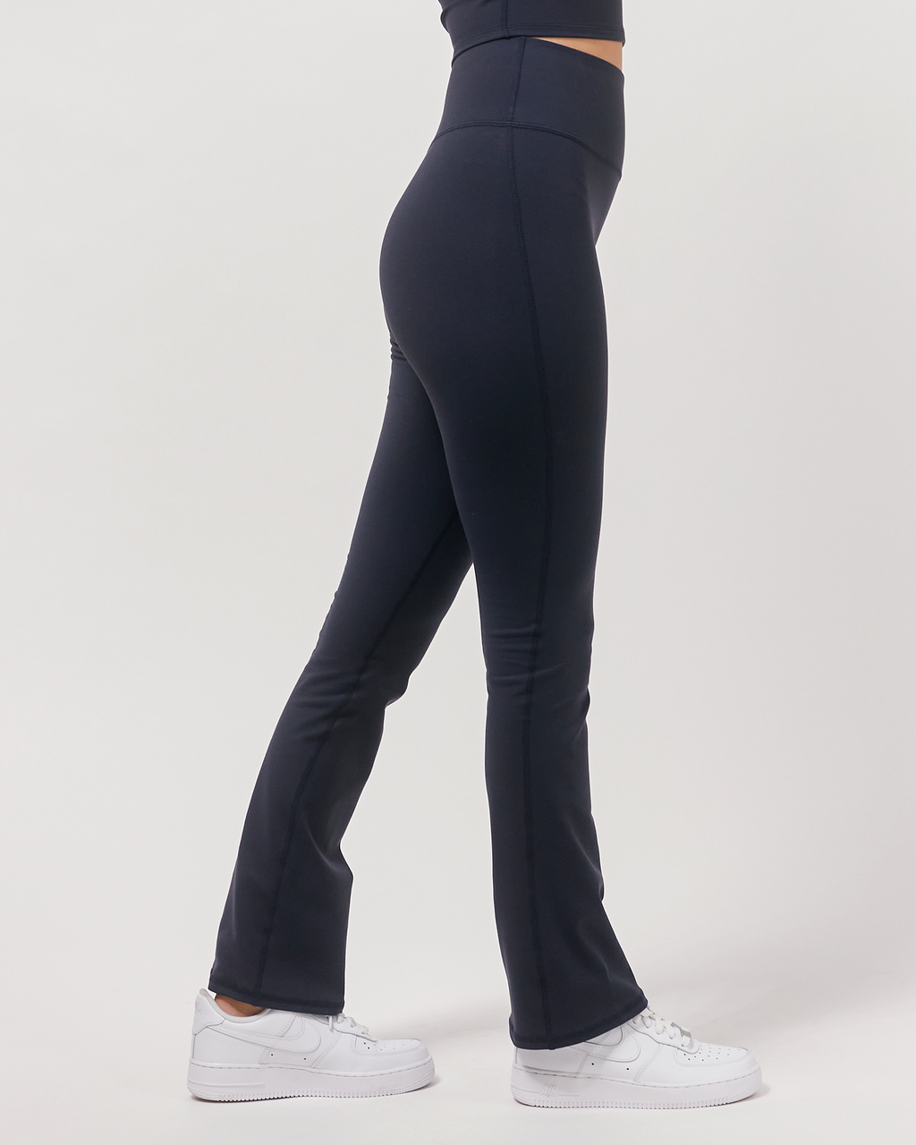 Navy blue flared pants worn by a person on a white background