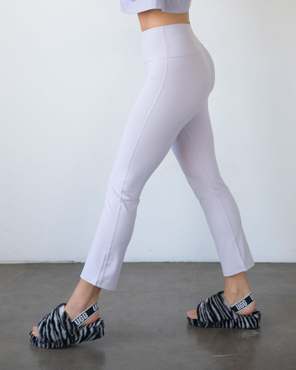 Person wearing light purple leggings and zebra print sandals on a plain background