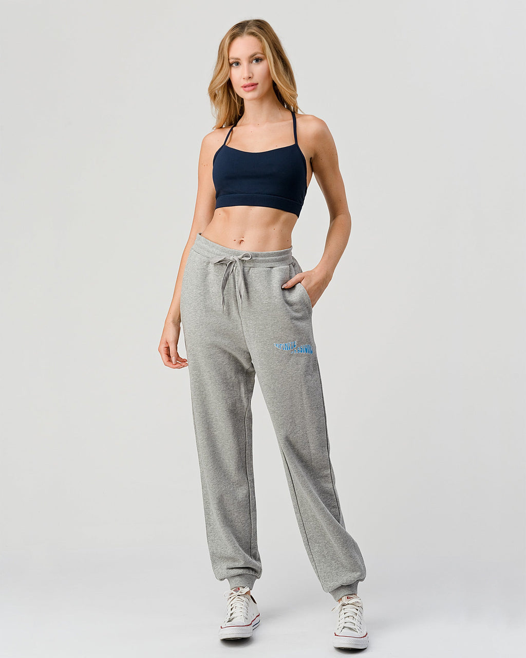 Woman wearing gray sweatpants with a logo on a white background