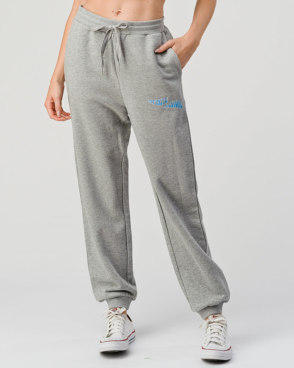 Person wearing gray sweatpants with a logo on a light gray background