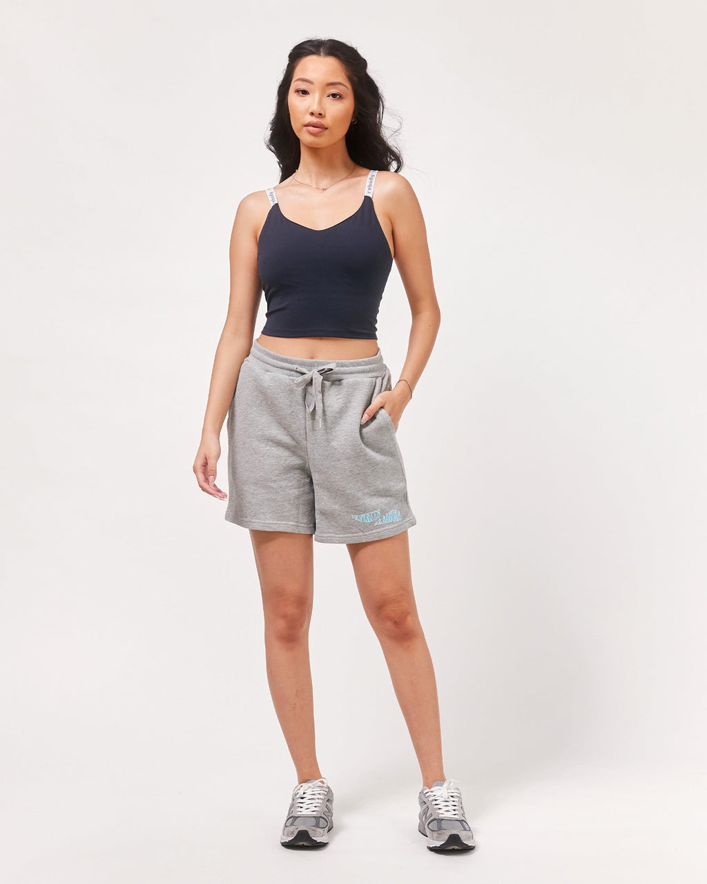 Woman wearing a black tank top and gray shorts on a white background