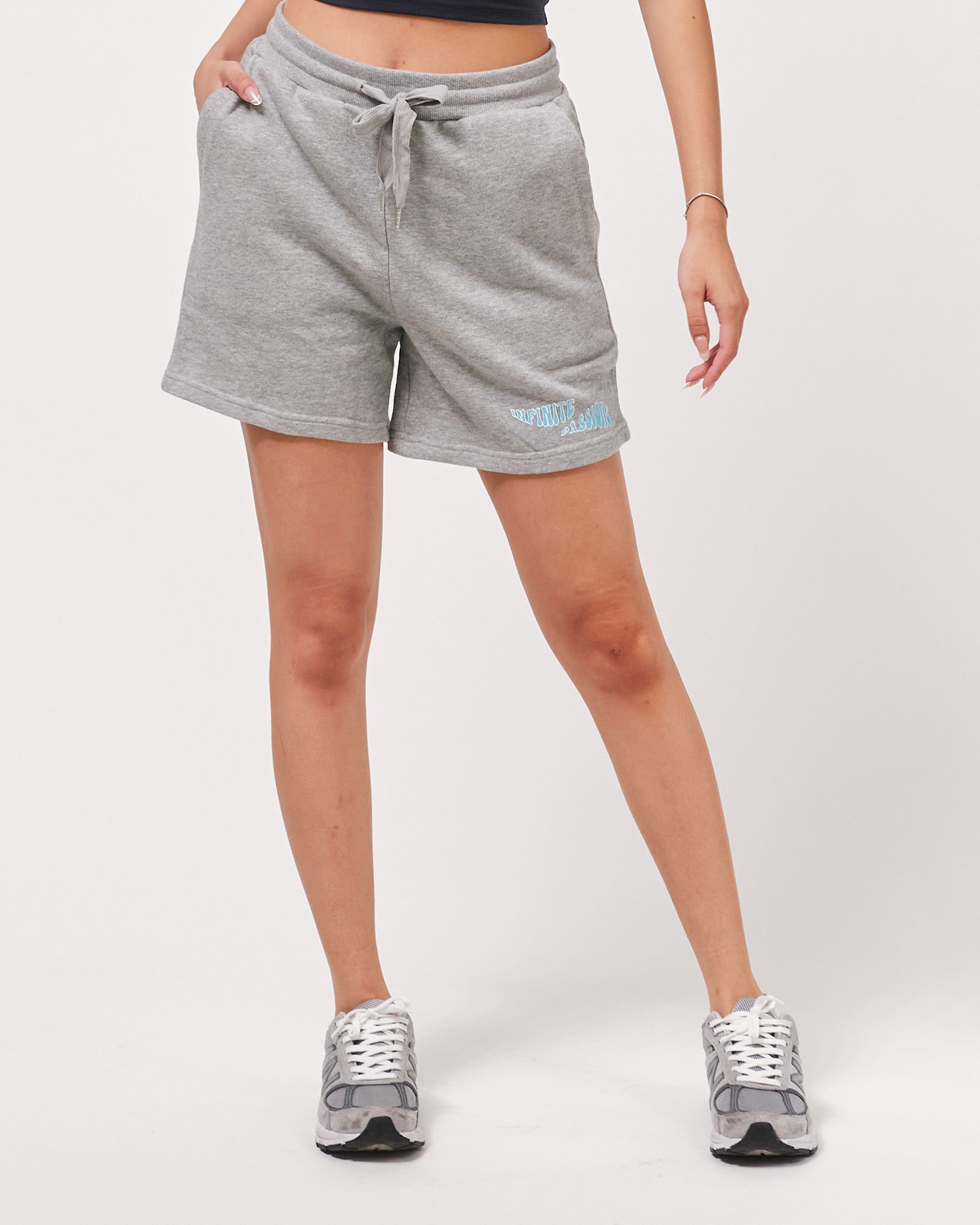 Person wearing gray shorts with a brand logo on a white background