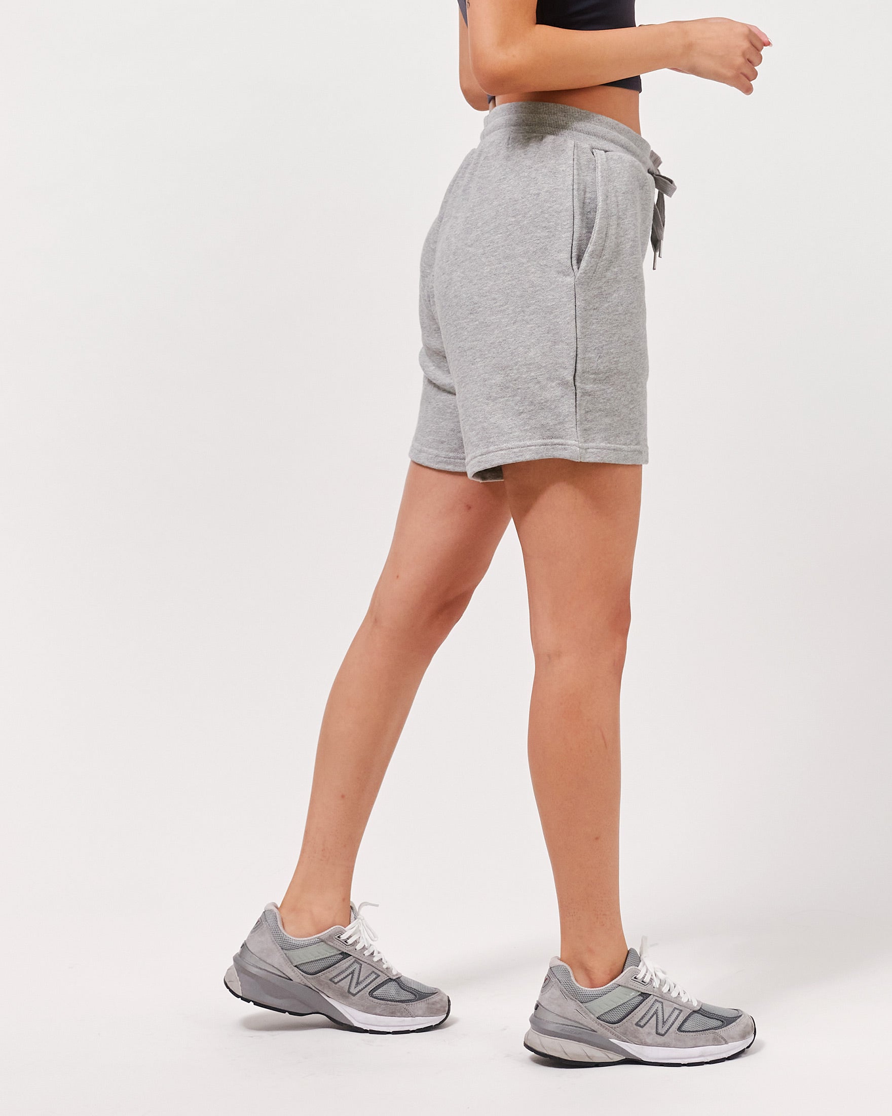 Person wearing gray shorts and gray sneakers on a white background