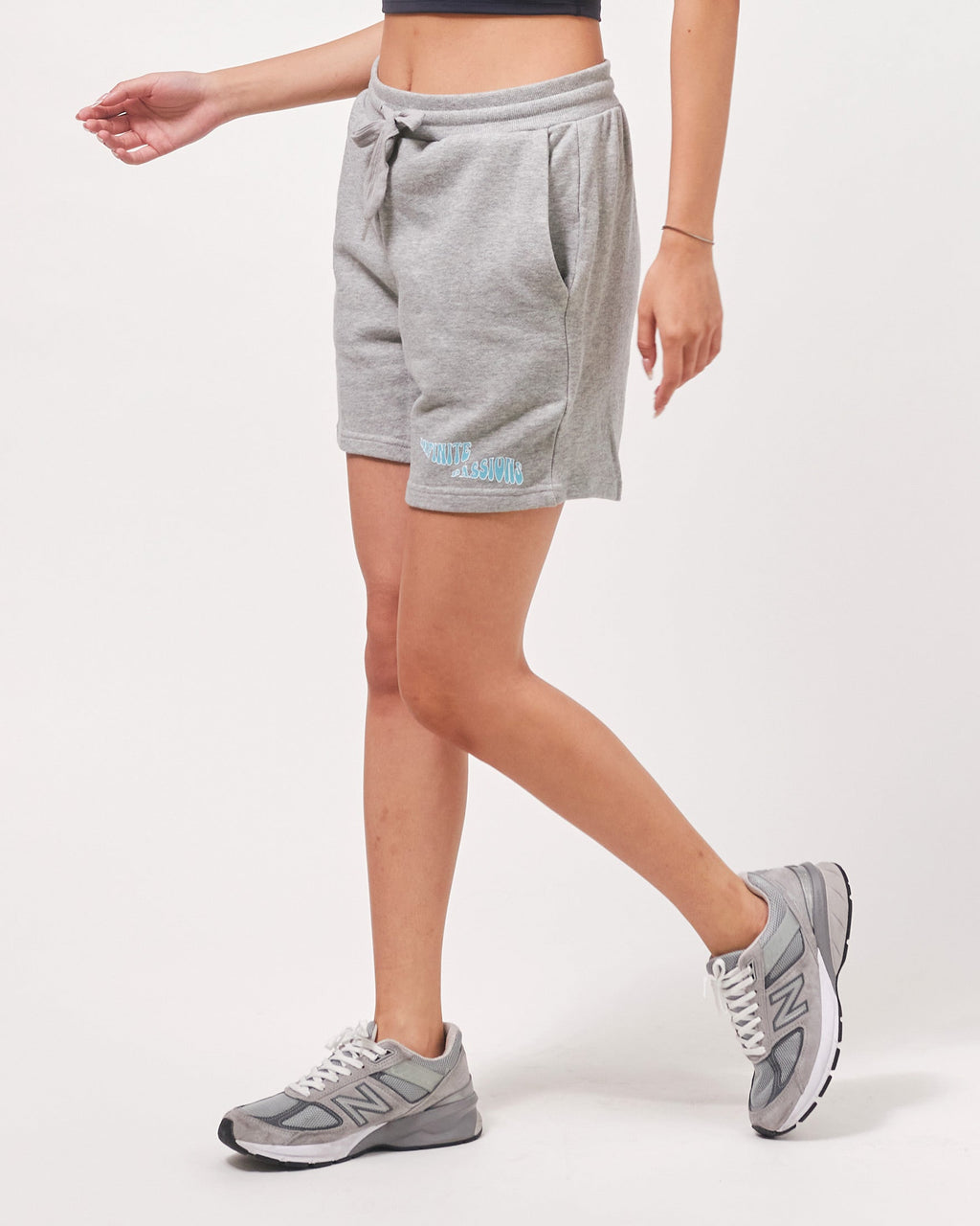 Person wearing gray sweat shorts and sneakers on a white background