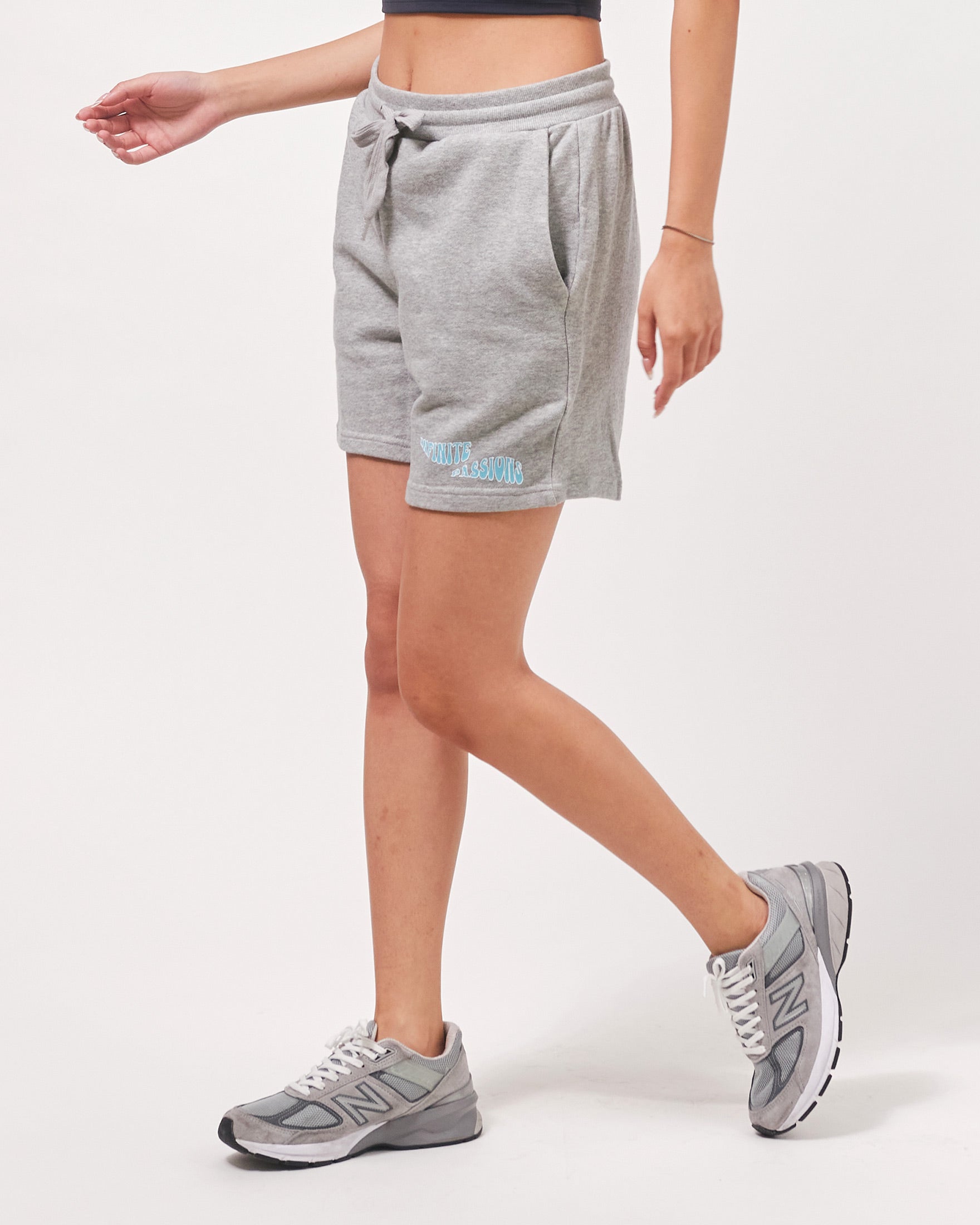 Person wearing gray sweat shorts and sneakers on a white background